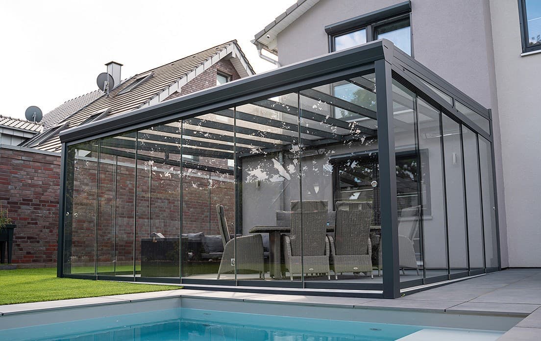 Premium anthracite glass-roofed veranda enclosing a patio beside a pool